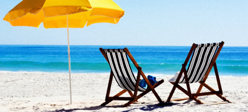 Two deckchairs and a yellow parasol on a deserted beach